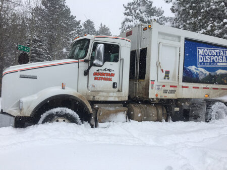 Garbage truck collecting trash in snowy Colorado neighborhood